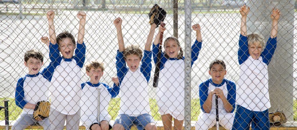 Little league baseball team cheering behind wire fence